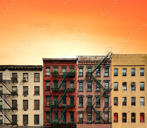 Obraz na płótnie Row of colorful old apartment buildings in Manhattan, New York City with warm yellow orange sunset sky background w salonie