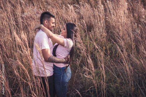 Pareja joven latina abrazados en un campo de espigas mirándose fijamente  photo