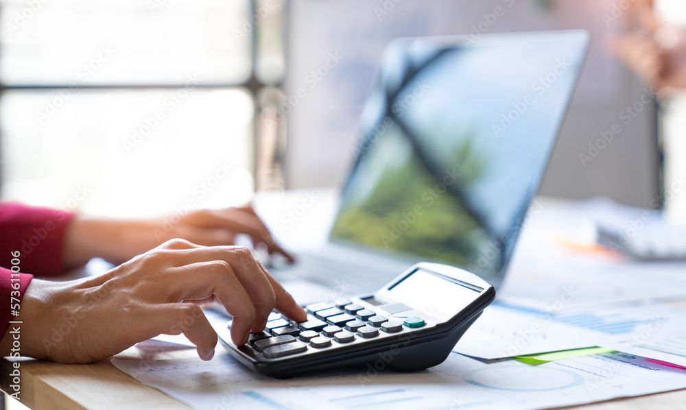 Asian businesswoman recording data on laptop Analyze charts, graphs and calculate financial reports with calculator in financial advisory office and accounting concept. Asian businesswoman recording data on laptop Analyze charts, graphs and calculate financial reports with calculator in financial advisory office and accounting concept.