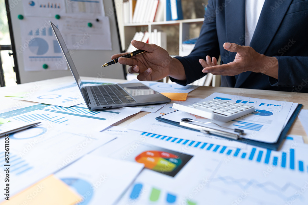 Young asian businessman analyzing data, charts, graphs and calculating financial reports in financial advisory office and accounting concept.