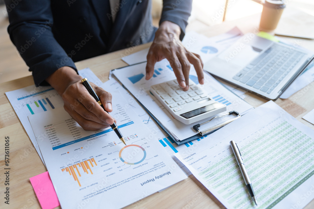 Young asian businessman analyzing data, charts, graphs and calculating financial reports in financial advisory office and accounting concept. Young asian businessman analyzing data, charts, graphs and calculating financial reports in financial advisory office and accounting concept.