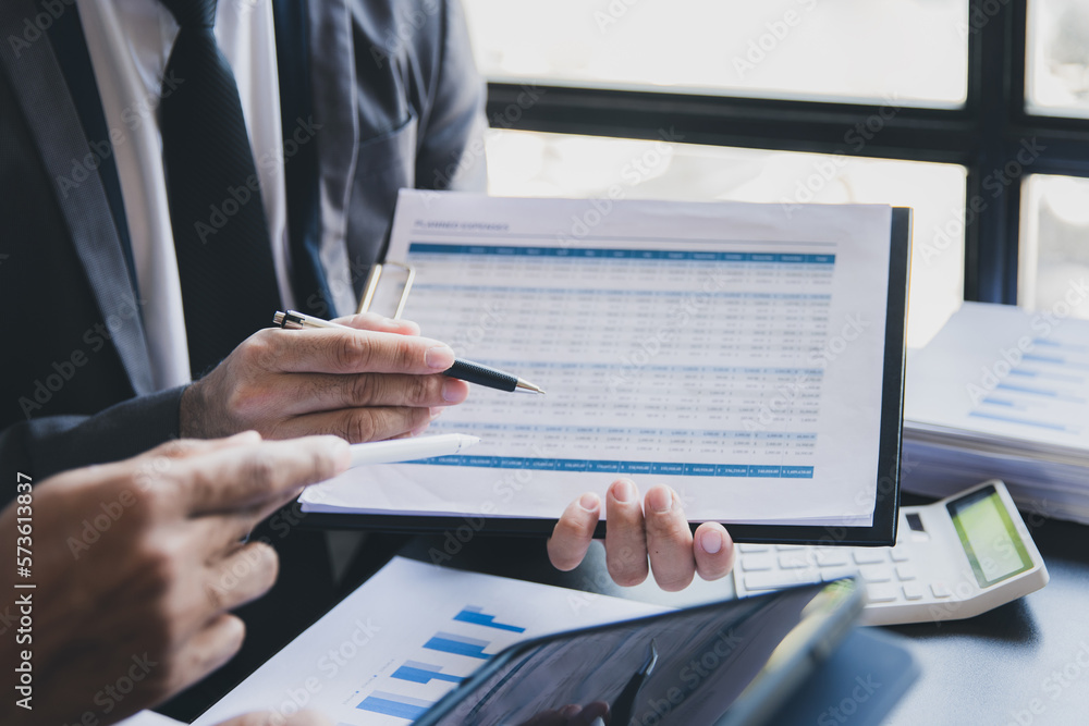 Close-up of two businessmen with pens pointing on report paper. Two Businessman discussing together in meeting room, investment projects. Close-up of two businessmen with pens pointing on report paper. Two Businessman discussing together in meeting room, investment projects.