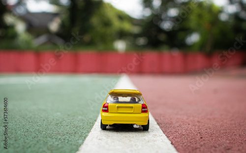 A yellow toy car at the border line of a court.