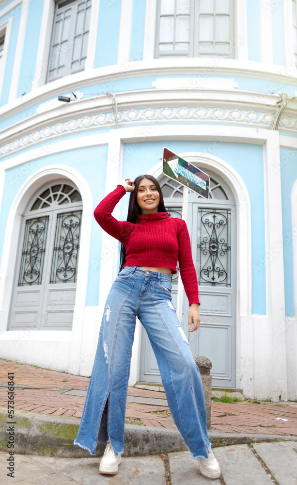Latin Happiness in a Historical Setting: Woman in a Red Blazer Posing in Front of a Vintage Blue House Latin Happiness in a Historical Setting: Woman in a Red Blazer Posing in Front of a Vintage Blue House