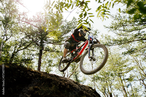 downhill mountain biking rider jump hill in sunlight