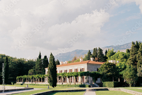 Villa Milocer in a green garden with mountains in the background. Montenegro