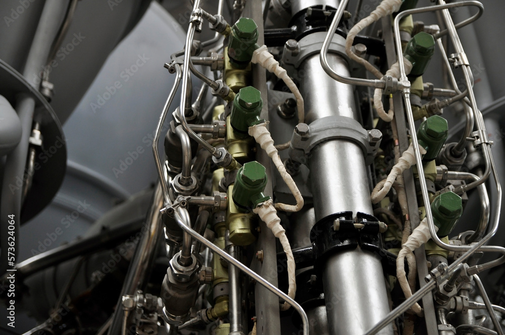 Obraz premium A close-up of a rocket engine with multiple pipelines supplying fuel and coolant to the combustion chamber. Jet engine with many titanium and stainless steel parts.