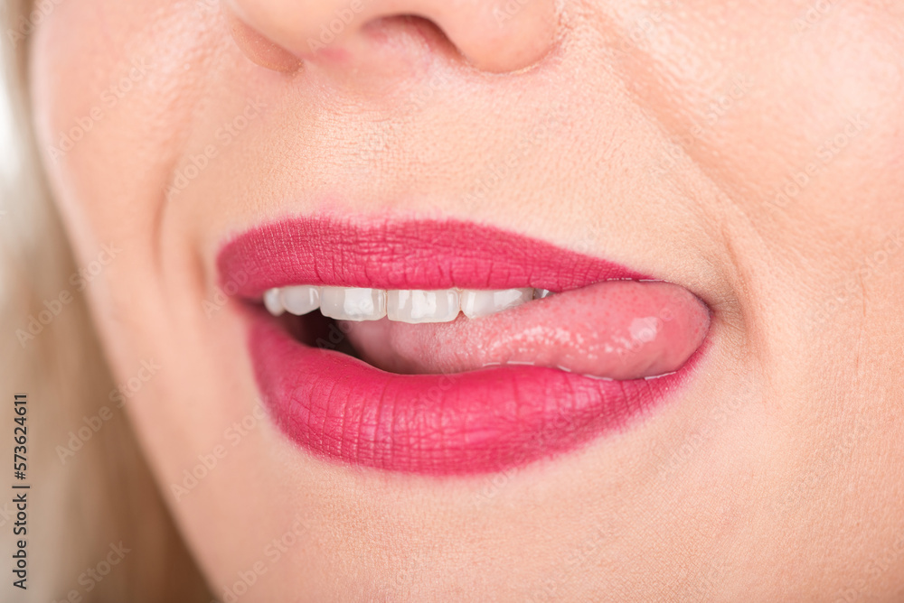 Woman Face with Open Mouth And Tongue Out. Bright Red Lipstick in Use and White Teeth.