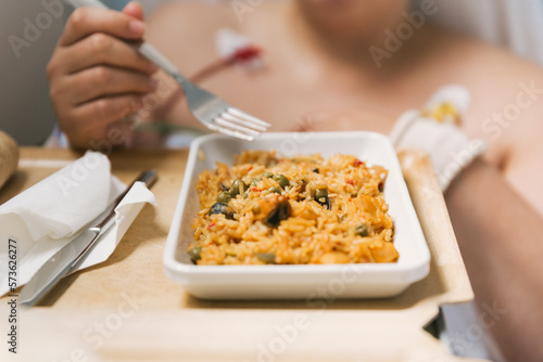 Female patient eating food in the hospital room.