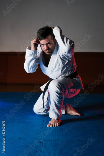 martial arts instructor in combat stance with kimono and black belt on a tatami mat