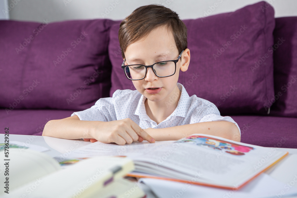 Young boy reading book at home. 
Education, childhood, homework and school concept.