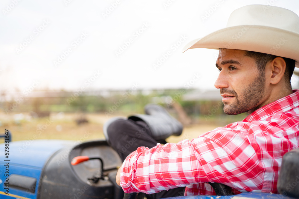 Handsome Middle East Asian man sitting on tractor and relaxing. Male farmer wearing a hat and relaxing on tractor.