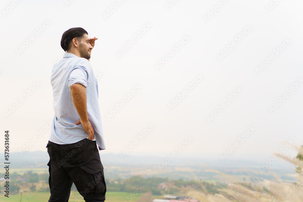 Happy handsome Middle - East Asian man standing on the mountain and making a relaxation with a beautiful landscape view. Man climb up on the top of mountain and posing for photography. Happy handsome Middle - East Asian man standing on the mountain and making a relaxation with a beautiful landscape view. Man climb up on the top of mountain and posing for photography.