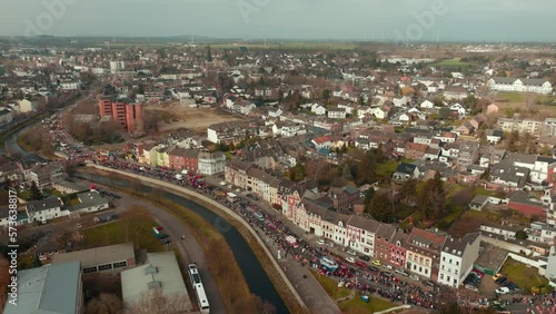 Zoom Out Drohnenaufnahme während eines Rosenmontagzuges, der das gesamte Dorf zeigt photo