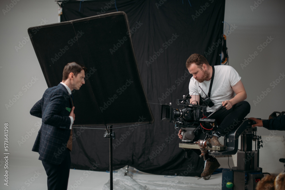 Professional male actor works in the frame on the set. Shooting with a car on a large white cyclorama. Professional male actor works in the frame on the set. Shooting with a car on a large white cyclorama.