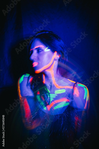 A beautiful young girl with makeup from ultraviolet paints smokes. Releases smoke from the mouth. Holiday of colors holly. Bright  colorful  festive coloring book. Fluorescent makeup on the face.