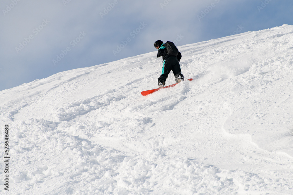 sportive man on snowboarder riding freeride on powder snow down the slope