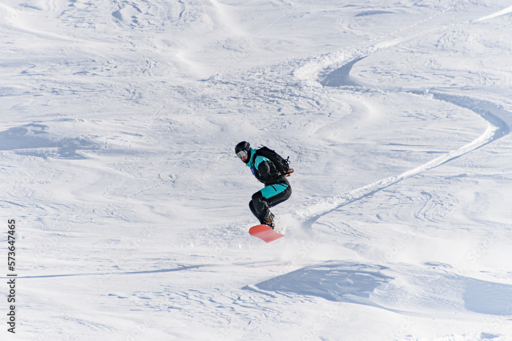 Freerider on snowboard skillfully ride down and jump at deep fresh snow in Gudauri Georgia