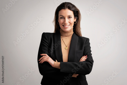 Confident mid aged woman wearing black blazer and standing at isolated background