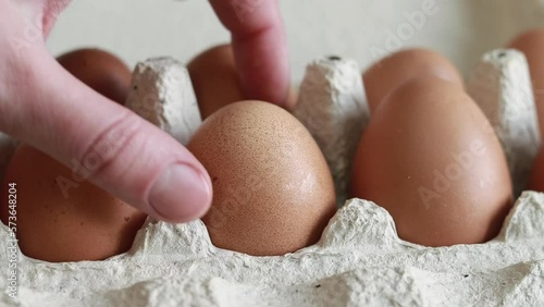 A woman's hand takes an egg from a cardboard box. Fresh raw eggs in a paper egg container. Opening the egg pack, close up. Fresh Protein Food photo