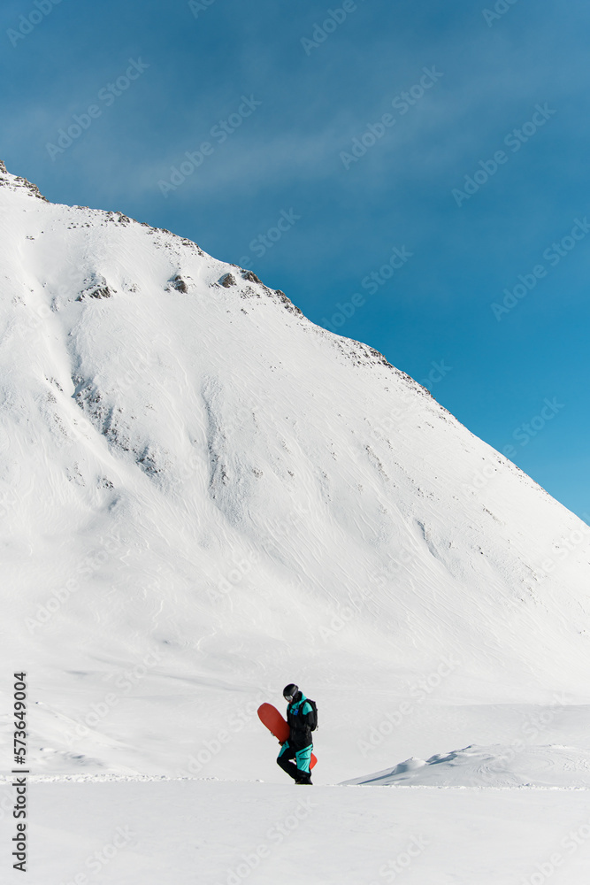 great view of man freerider with snowboard walks against winter mountain landscape