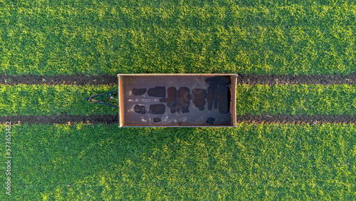 Hänger von einem Traktor steht auf einem grünen Feld mit Spuren von oben Top down, Hintergrund, Vogelsicht, Nahaufnahme