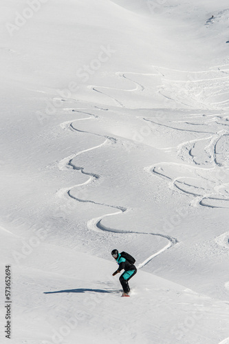 Fotografie wonderful view of a snow-covered mountain slope and a man on a snowboard slides