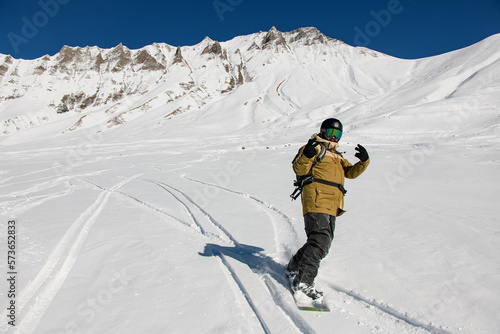 snowboarder riding freeride on snow down the slope against the backdrop of the mountains