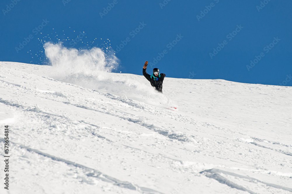 sportive man snowboarder skilfully descends down a snowy mountain slope