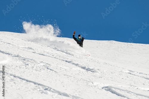 sportive man snowboarder skilfully descends down a snowy mountain slope