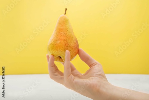 Close-up of a woman's hand holding a yellow pear. Selective focus.
