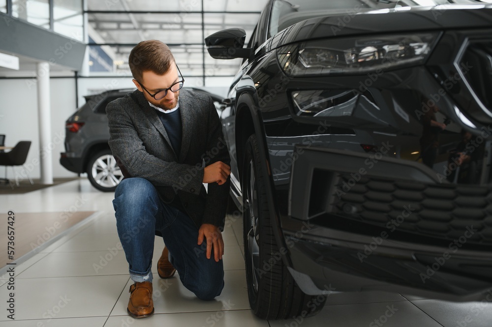 Man adult customer male buyer client wears classic suit white shirt chooses auto wants to buy new automobile touch check car in showroom vehicle salon dealership store motor show indoor. Sales concept Man adult customer male buyer client wears classic suit white shirt chooses auto wants to buy new automobile touch check car in showroom vehicle salon dealership store motor show indoor. Sales concept
