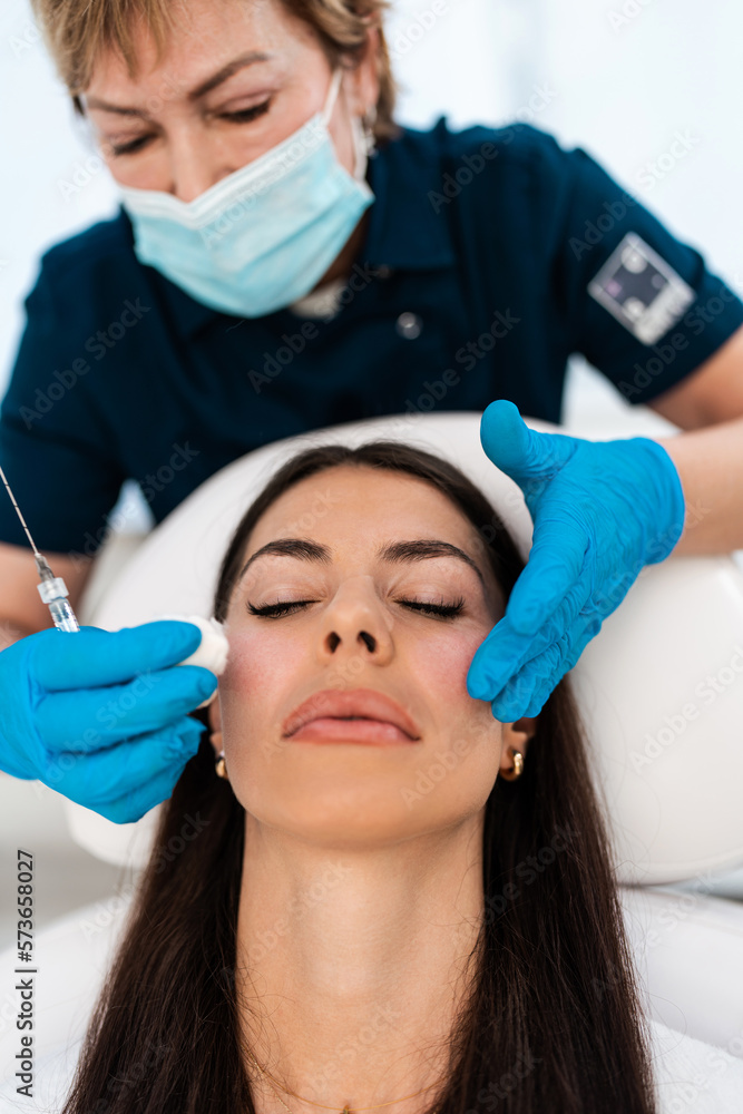 Beautician is contouring the woman's cheekbones with hyaluronic acid