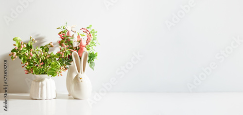 Spring flowers in a vase and easter bunny on a light background. Easter background with copy space