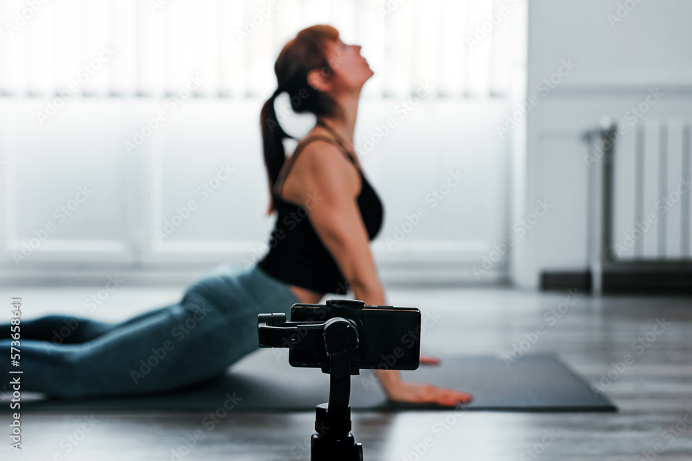 Fototapeta premium Woman Doing Exercise in Front of Phone for Streaming