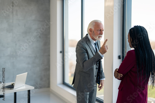 Fotografi Angry senior businessman harassing young businesswoman intern at work threatenin