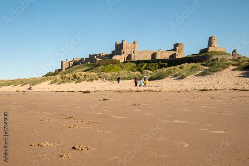 Bamburgh Castle on a hot summer s day in 2022. Northumberland  UK. Tourists on beach