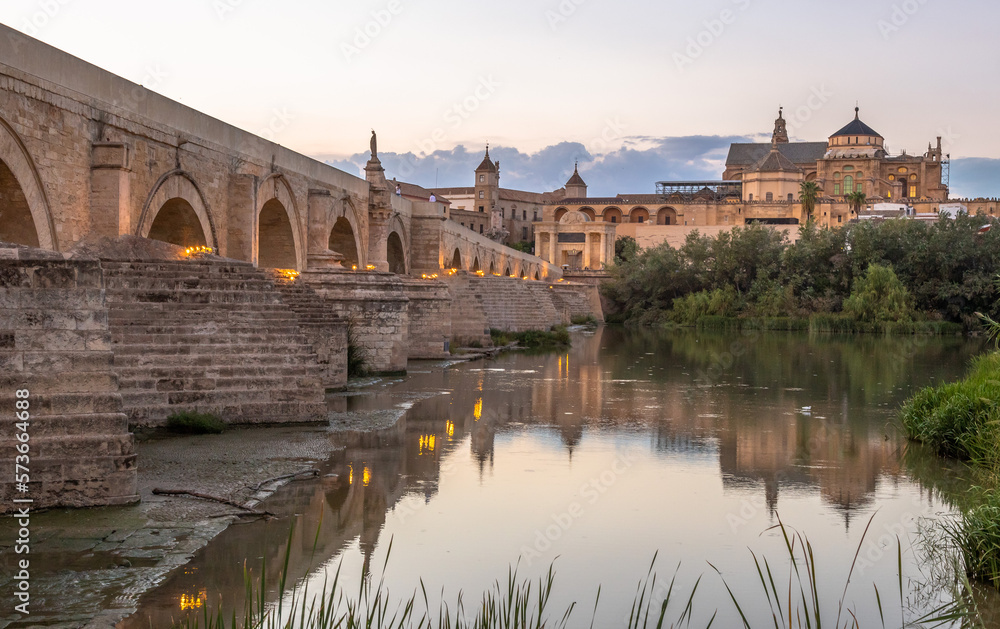 Exposure at sunset of the Roman bridge of and the Mosque–Cathedral of Cordoba in the background with the Guadalquivir river in the foreground