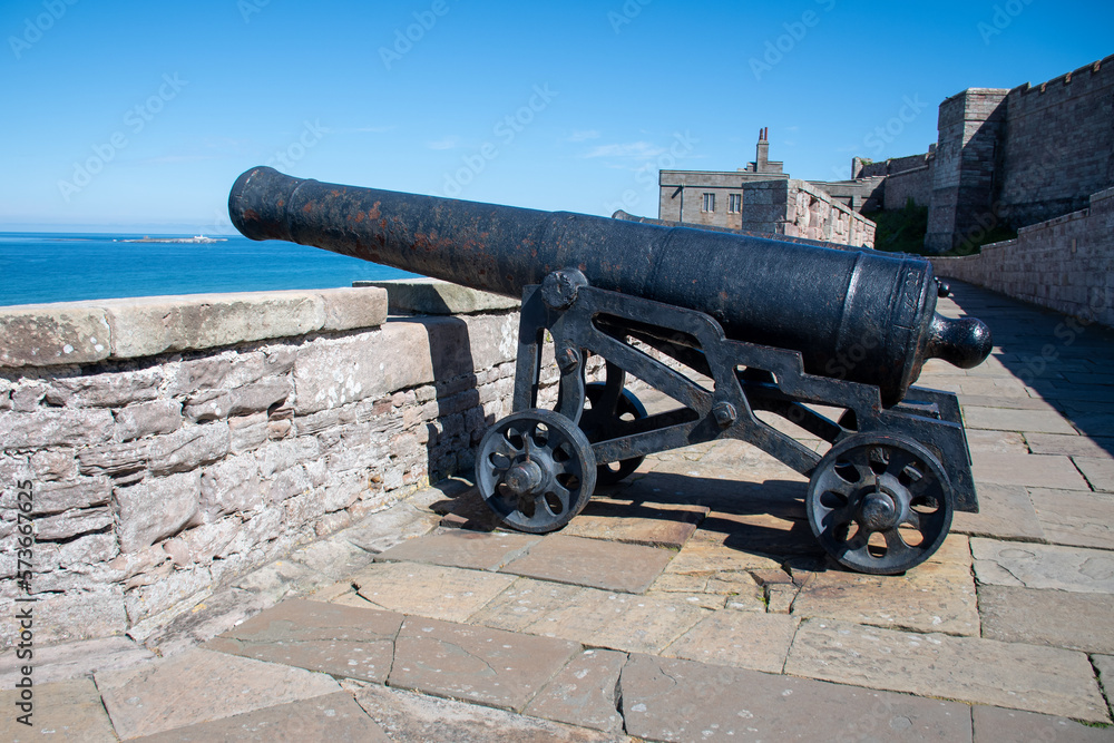 Cannon pointing out towards sea in the grounds of Bamburgh Castle, Northumberland, UK