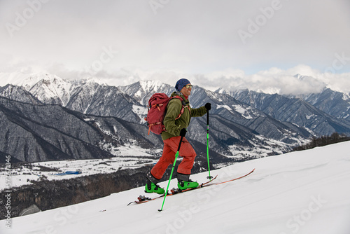 side view of active male skier walking against winter mountain landscape
