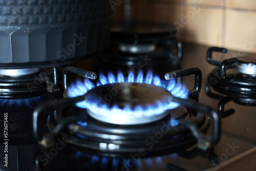 Spalanie gazu ziemnego na kuchennej kuchence gazowej. Panel ze stali z pierścieniowym palnikiem gazowym na czarnym tle. Blisko. 