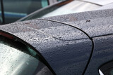 Krople deszczu - wody na karoserii samochodu i na szybie.