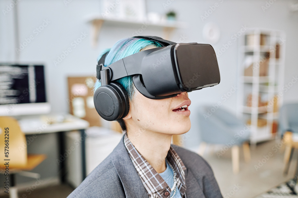 Side view portrait of young man wearing VR headset in office working on immersive reality project Side view portrait of young man wearing VR headset in office working on immersive reality project
