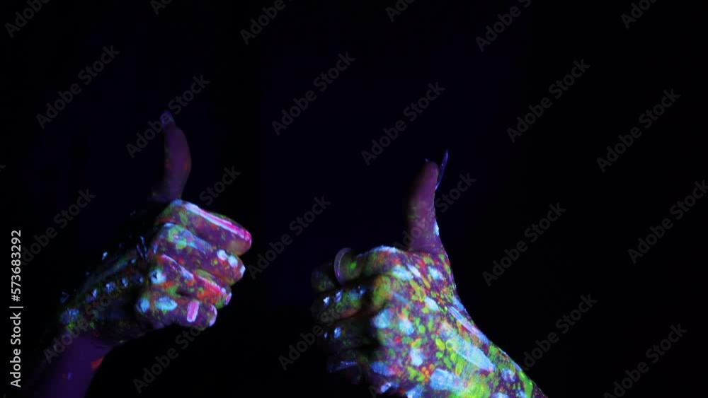 A hand with a fluorescent ethnic pattern shows a thumbs up. Fluorescent paint, body art concept. Glows in the dark. Gestures, symbols, hand movements. A hand with a fluorescent ethnic pattern shows a thumbs up. Fluorescent paint, body art concept. Glows in the dark. Gestures, symbols, hand movements.