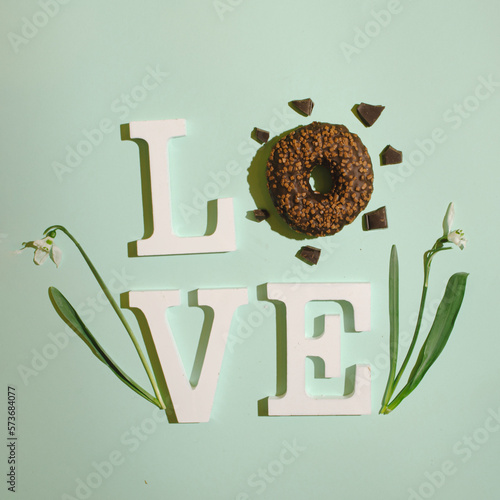 Donut like the letter O in the inscription LOVE, on a mint green background photo