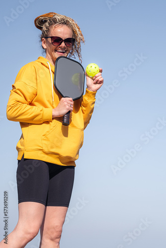 portrait woman player pickleball game over blue sky, pickleball yellow ball with paddle, outdoor sport leisure activity © Наталия Кузина