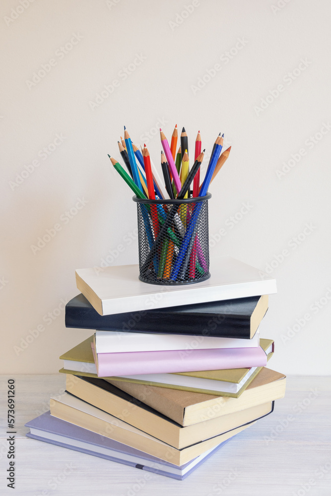 Pencil holder with colored pencils and stack of books on rustic table. Copy space Pencil holder with colored pencils and stack of books on rustic table. Copy space