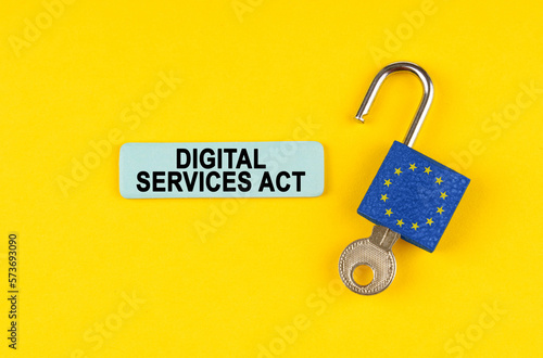 On the yellow surface is an open lock with a key and a sticker with the inscription - Digital services act photo