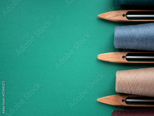 Wooden boat shuttles for handloom and cones with yarn, copy space. Concept of weaving tools