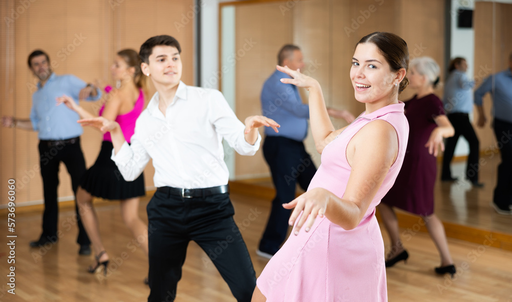 Fototapeta premium young couple enthusiastically dancing social latin cha-cha-cha dance in dance studio